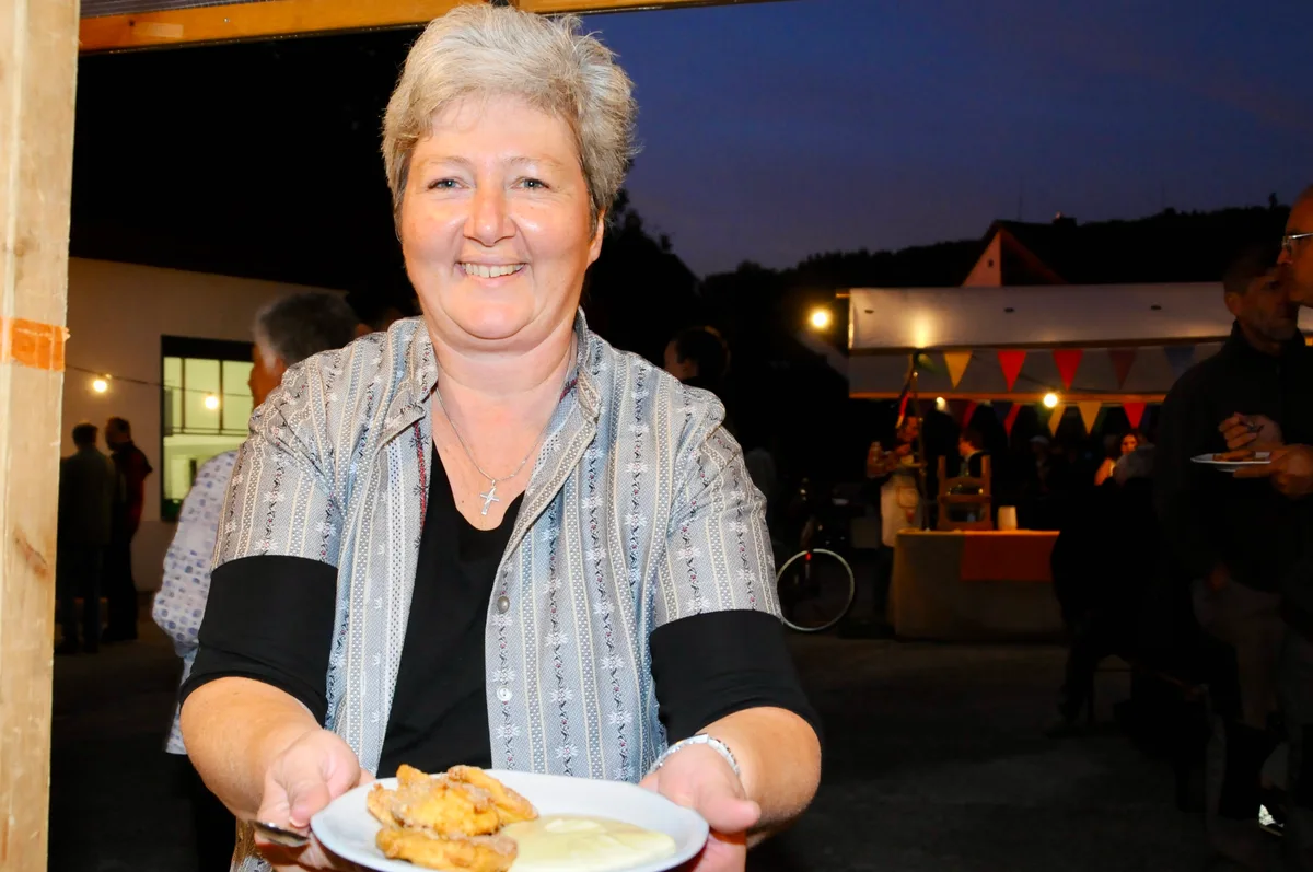 Man sieht eine Frau mit einem Teller Öpfelchüechli.